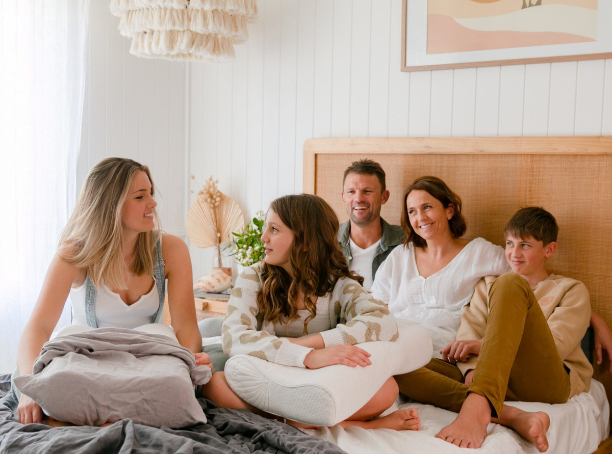 Family relaxing together on a bed with Posture Form pillows